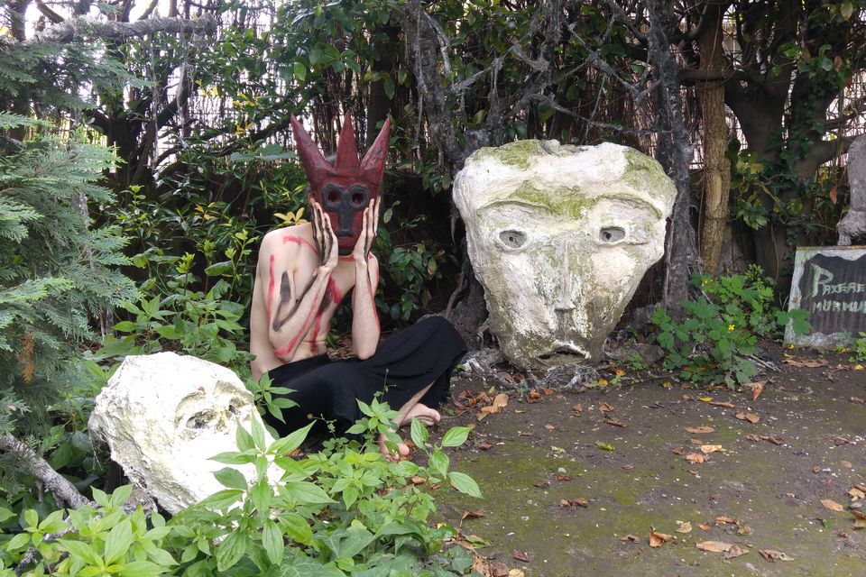 Performance shamanique avec masque en bois au milieu de sculptures de plâtre par l'artiste Arnaud Degouy